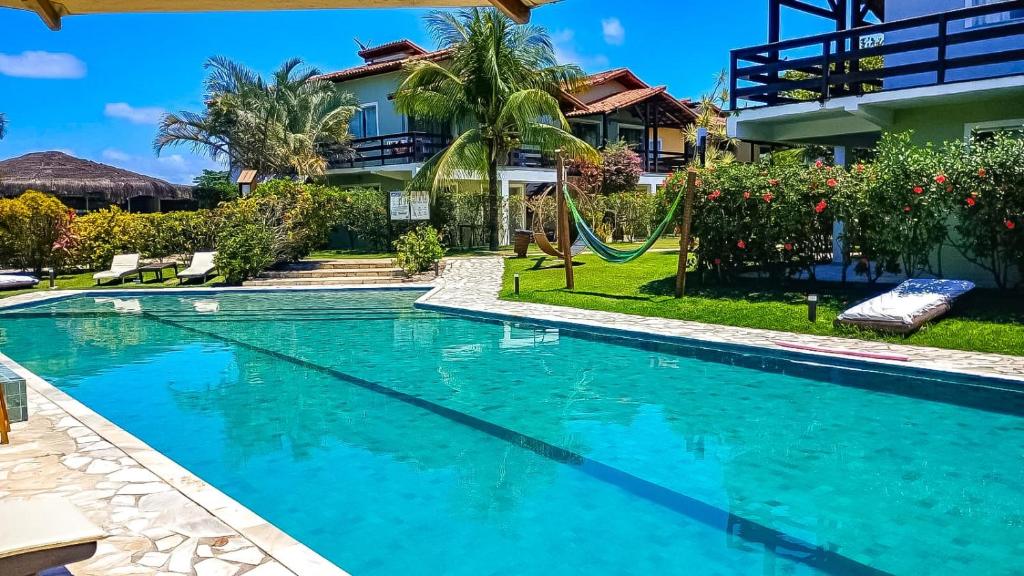 a swimming pool in front of a house at Village Muta in Porto Seguro