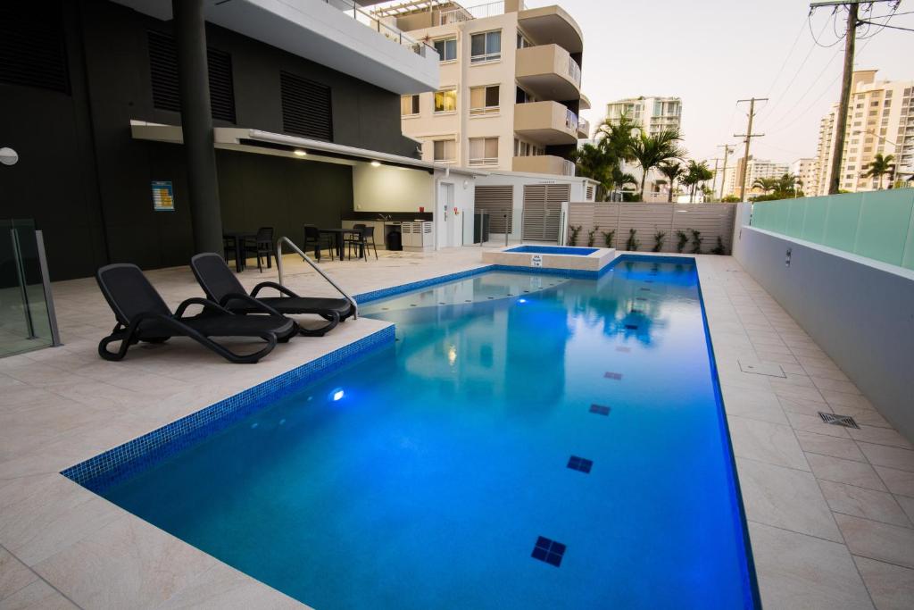 a swimming pool with two chairs in a building at Verve on Cotton Tree in Maroochydore