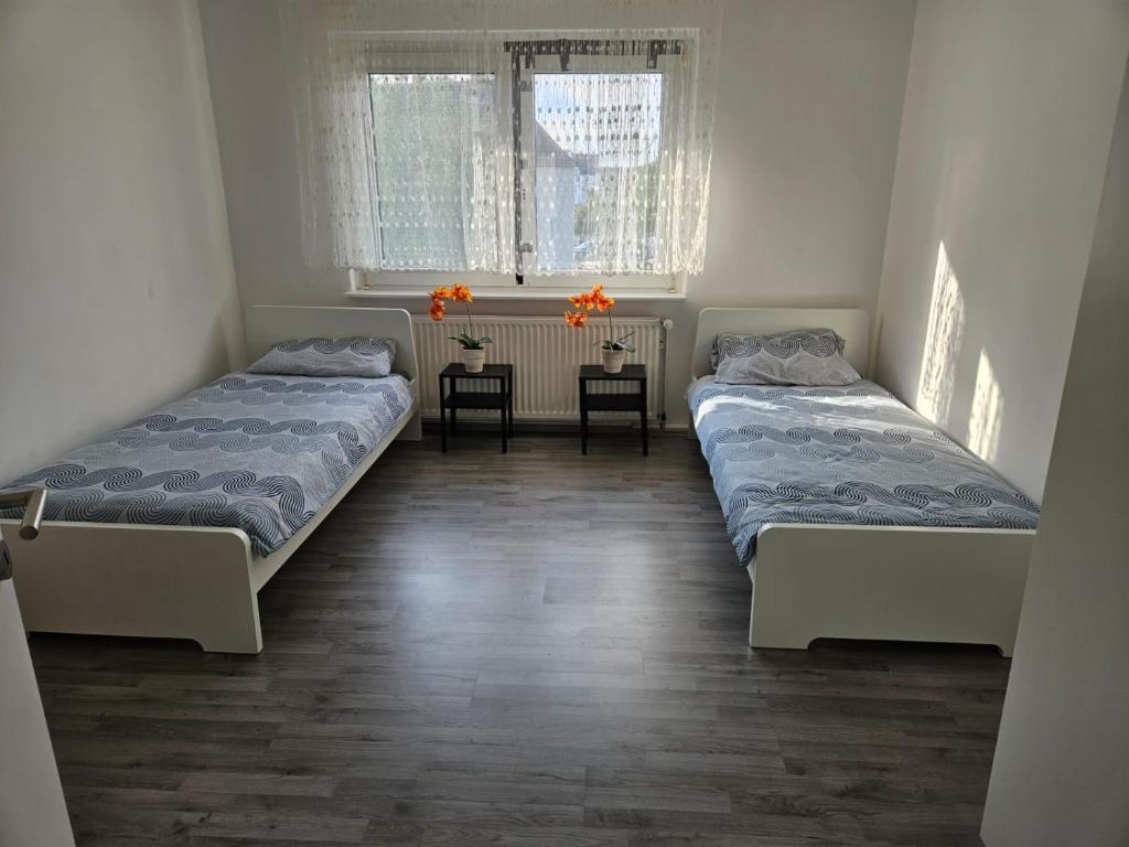 two beds in a room with two chairs and a table at Charmante Ferienwohnung in Herne-Mitte in Herne