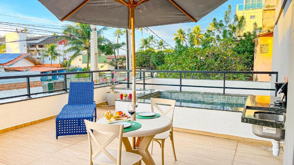 a table and chairs on a balcony with an umbrella at Melhor localização Porto Galinhas 50M DO MAR E CENTRINHO - COM E SEM PISCINA PRIVATIVA Family Flats Porto de Galinhas in Porto De Galinhas