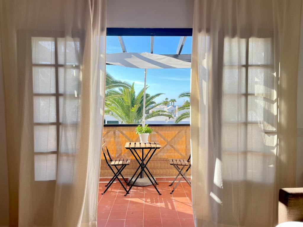een kamer met een balkon met een tafel en een patio bij Encanto del mar, shared pool in Puerto del Carmen