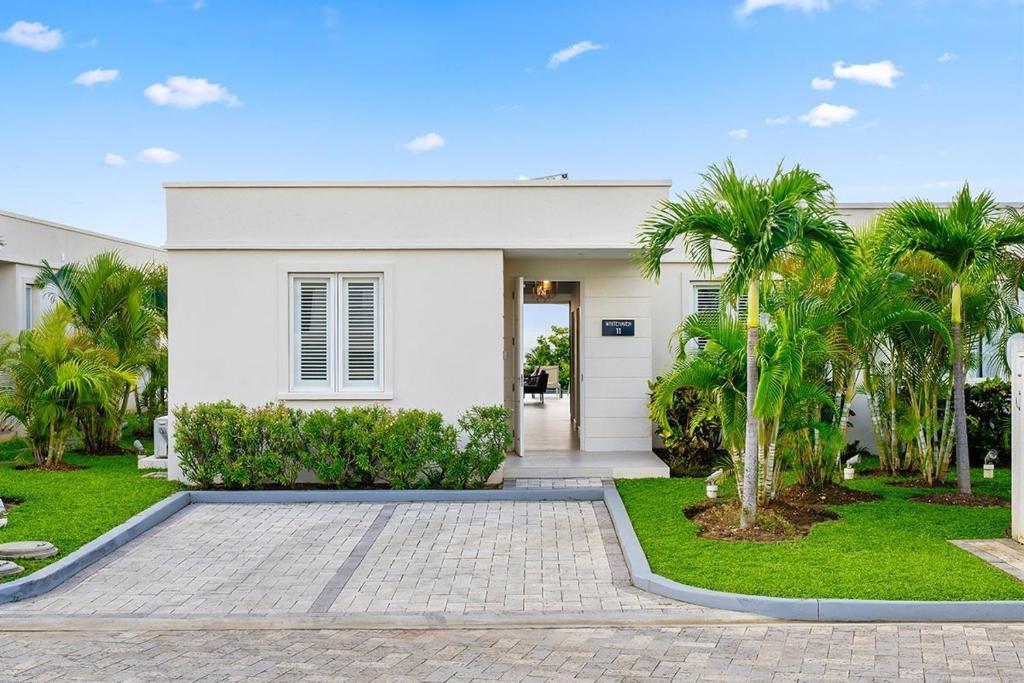 une maison blanche avec des palmiers devant dans l'établissement Westmoreland Hills 11-Whitehaven villa, à Saint James