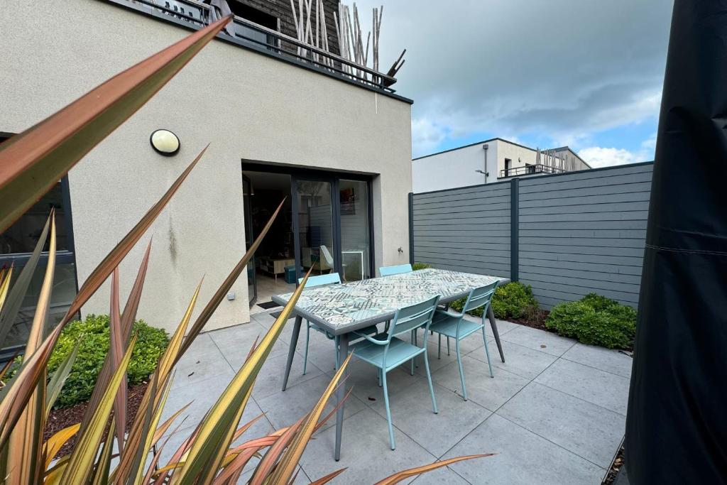 un patio avec une table et des chaises et un bâtiment dans l'établissement Apartment 5 minutes from the beach, à Lion-sur-Mer