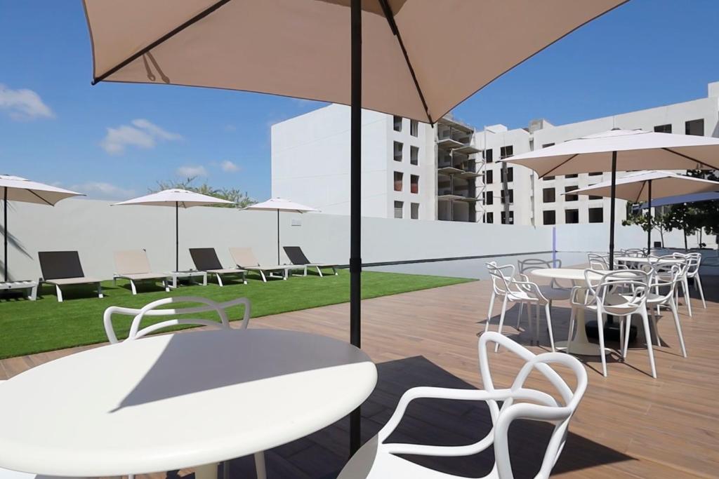 a patio with white tables and chairs and umbrellas at Lumina at Marea Cabo San Lucas in Cabo San Lucas