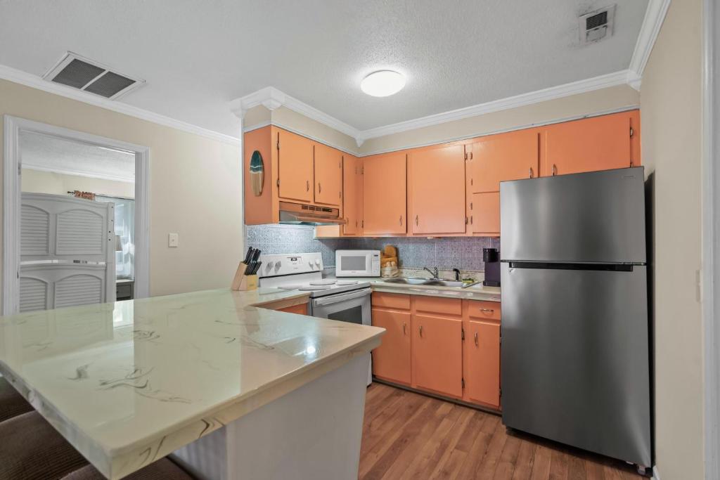eine Küche mit orangefarbenen Schränken und einem Kühlschrank aus Edelstahl in der Unterkunft Domingos Beach Bungalow- Surfs Up in Myrtle Beach