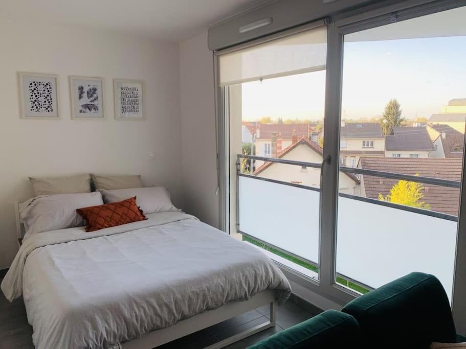 une chambre avec un lit et une grande fenêtre dans l'établissement Superbe Appartement avec parking sous sol gratuit, à Livry-Gargan