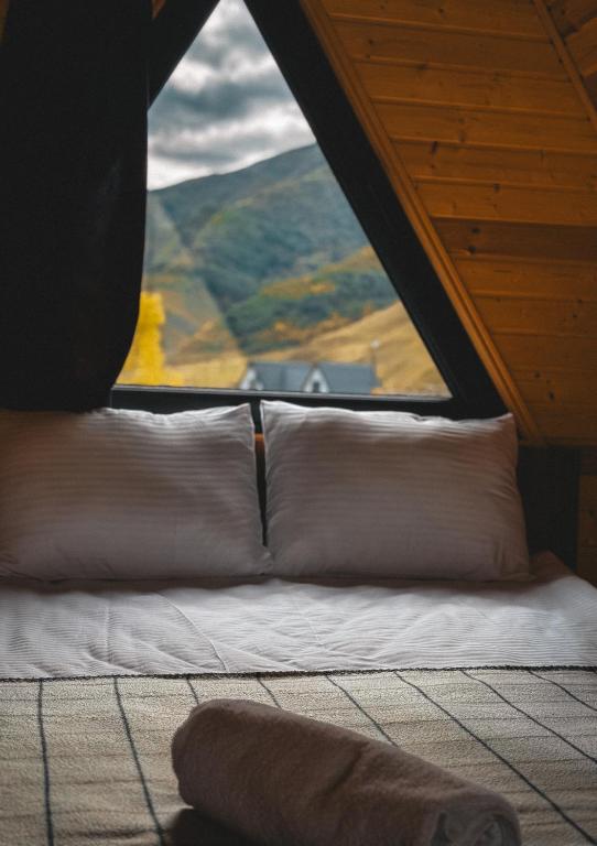 a bed with pillows in a room with a window at Gold cottages Kazbegi in Kazbegi
