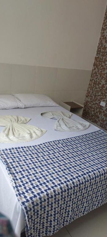 a bed with a blue and white checkered blanket at Apê Aconchegante in Recife