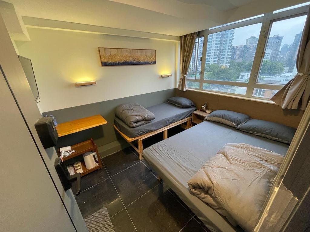 una piccola stanza con due letti e una finestra di 香港榆臨賓館 Yulam Guesthouse a Hong Kong