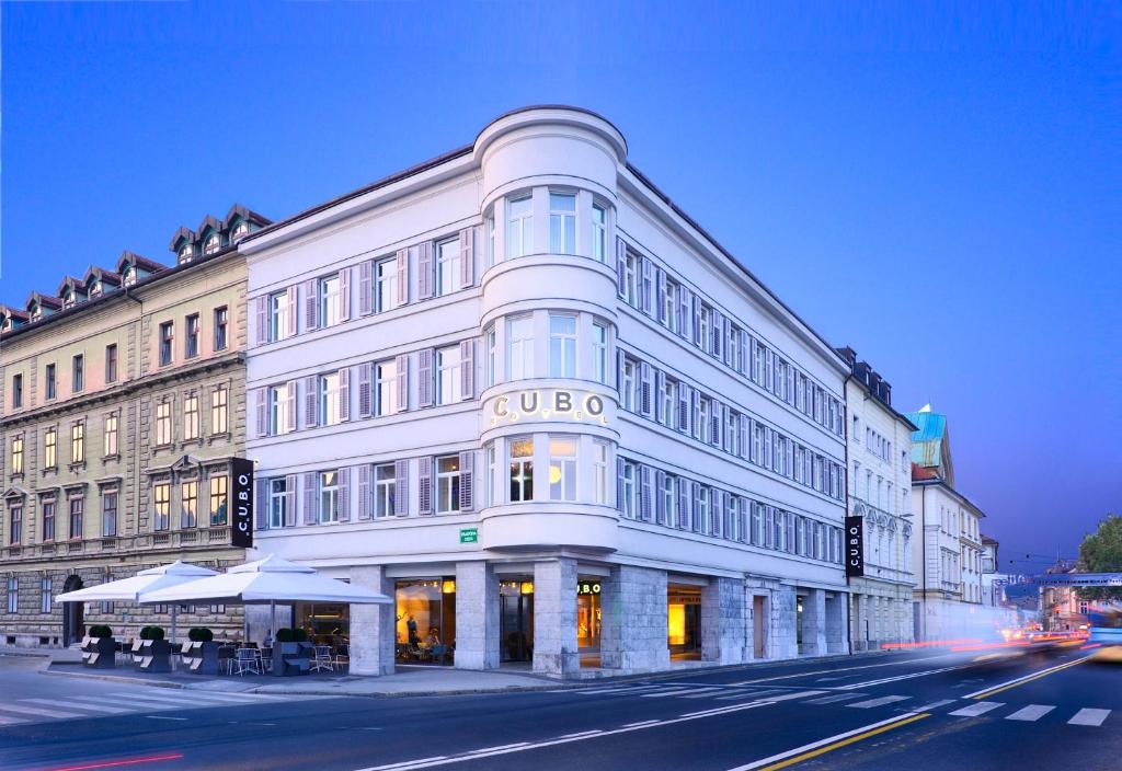 un grand bâtiment blanc au coin d'une rue dans l'établissement Hotel Cubo, à Ljubljana