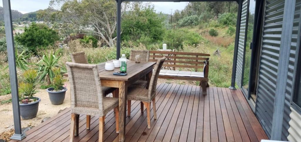 利斯戈Micro Mansion with big deck and views in Lovely Lithglow的甲板上配有一张木桌和椅子,甲板上设有长凳