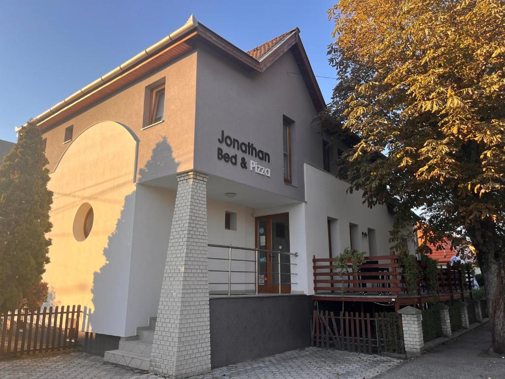 budynek z płotem przed nim w obiekcie Jonathan Bed&Pizza w mieście Komárom