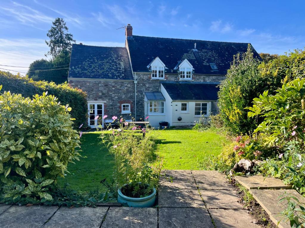 an old stone house with a garden in front of it at The Cottage in Abergavenny