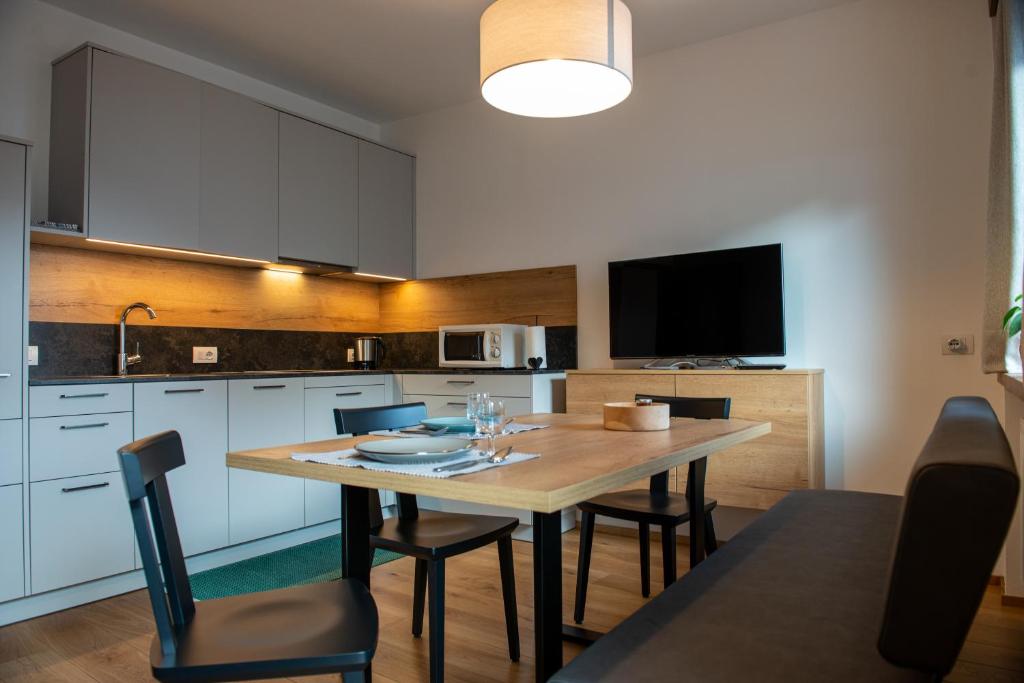 a kitchen with a table with chairs and a television at Krautgasser Appartements in San Candido