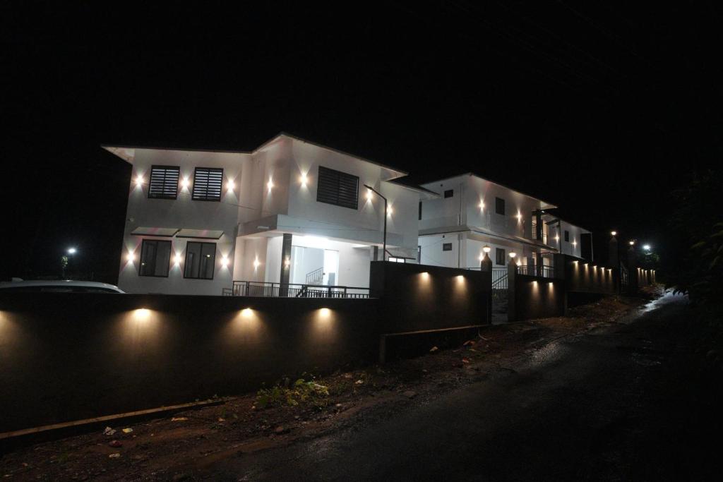 a white house with lights on a wall at night at Angel Valley Inn in Vayittiri