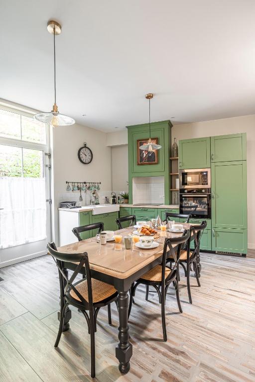 une cuisine avec des armoires vertes, une table et des chaises dans l'établissement La Grive - 400m Plage - Confort, à Étretat
