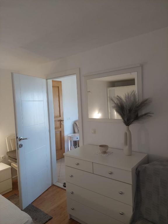 a white bedroom with a dresser and a mirror at VILLA Apartments Mate Cebalo in Lumbarda