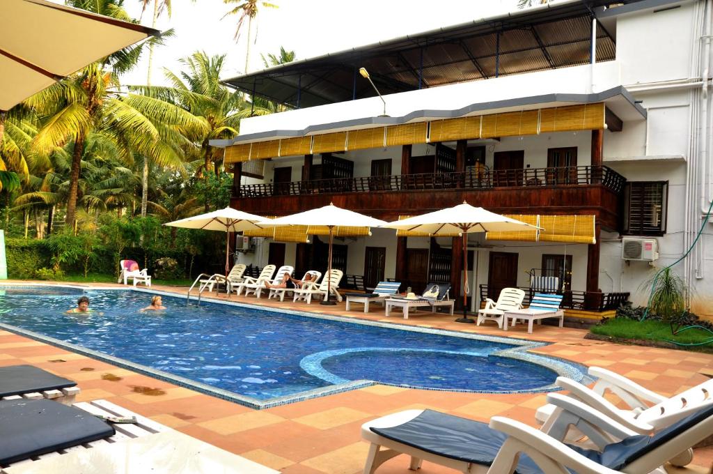 a pool with chairs and umbrellas in front of a building at Raja Park Beach Resort in Varkala