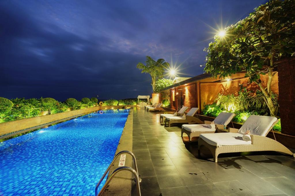 a swimming pool with lounge chairs and a resort at Vivanta Goa, Panaji in Panaji