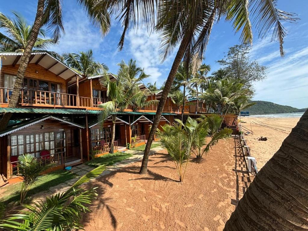 a resort on the beach with palm trees at Jardim a Mar in Agonda