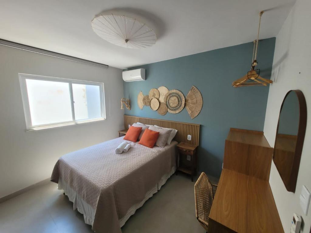 a bedroom with a bed with orange pillows and a window at Apartamento Boho Style Absolute piscina borda com borda infinita in Morro de São Paulo