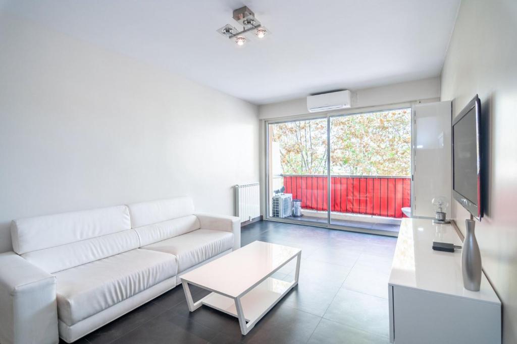 un salon avec un canapé blanc et une télévision dans l'établissement Beau 3P proche hippodrome - Parking privé, à Cagnes-sur-Mer