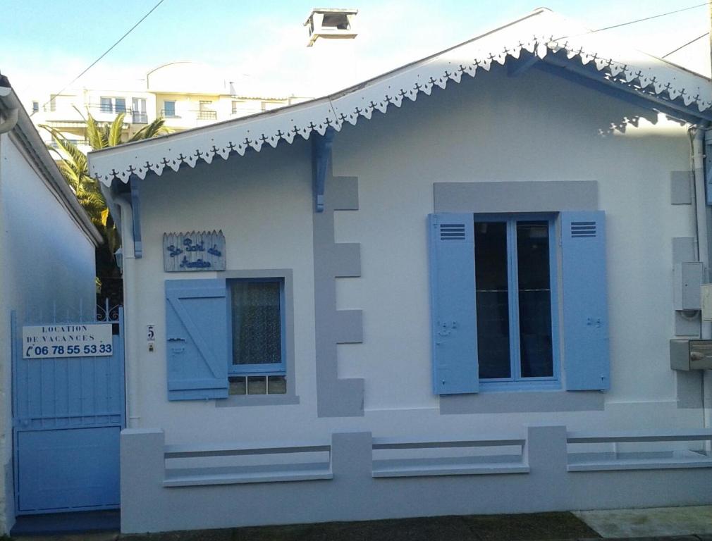 Cette petite maison blanche est dotée de fenêtres bleues et d'une porte. dans l'établissement La PART des ANGES, à Arcachon