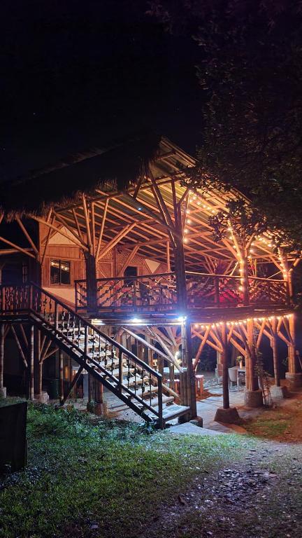 a wooden building with a staircase in front of it at night at Colibamboo Ecolodge Biocasa artesanal rodeada de naturaleza con jaccuzi y mucho más in Pacho