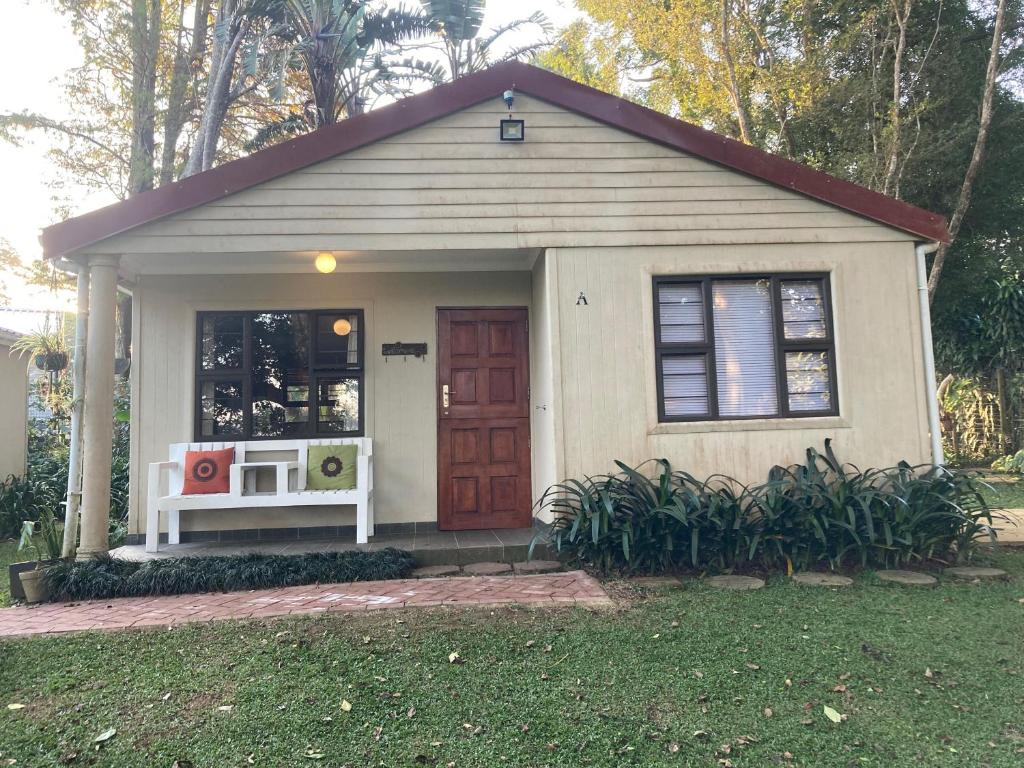 a small house with a red door in a yard at Khaled Estate Cottages - unit A in Hillcrest