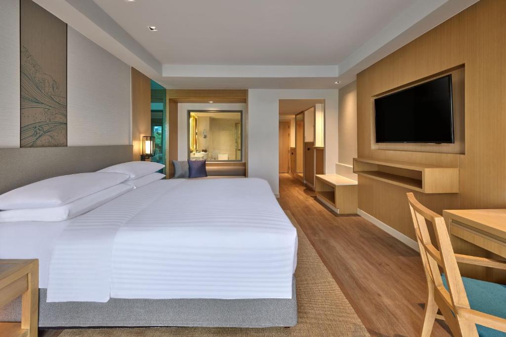 a bedroom with a large white bed and a television at Phuket Marriott Resort & Spa, Merlin Beach in Patong Beach