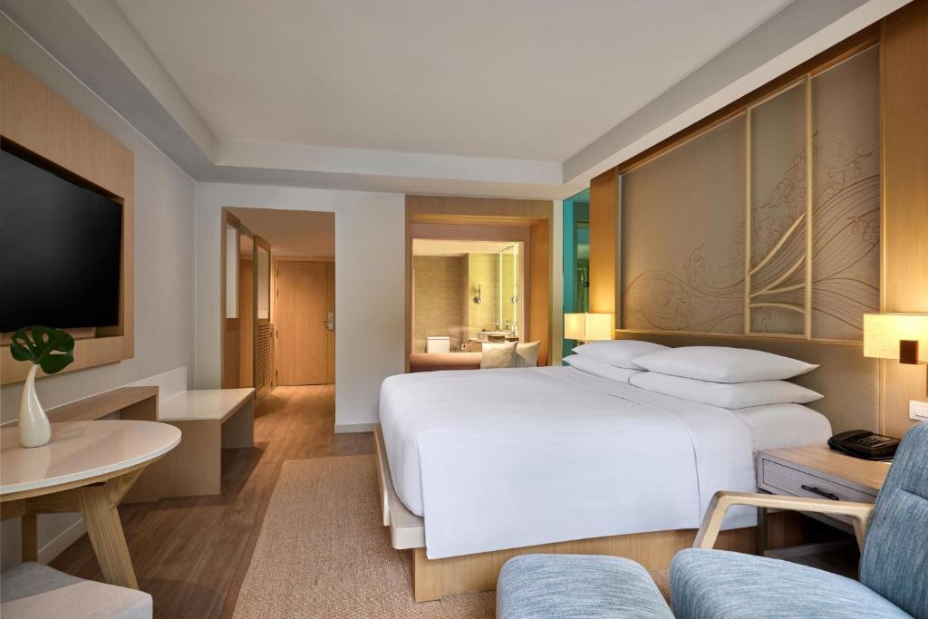 a bedroom with a large bed and a living room at Phuket Marriott Resort & Spa, Merlin Beach in Patong Beach