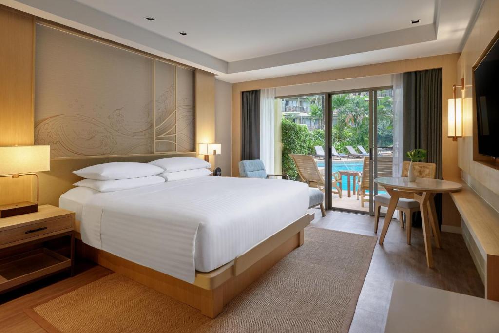 a bedroom with a large bed and a balcony at Phuket Marriott Resort & Spa, Merlin Beach in Patong Beach
