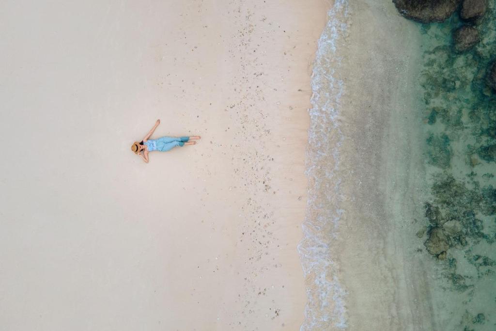 an overhead view of a person laying on a beach at Phuket Marriott Resort & Spa, Merlin Beach in Patong Beach