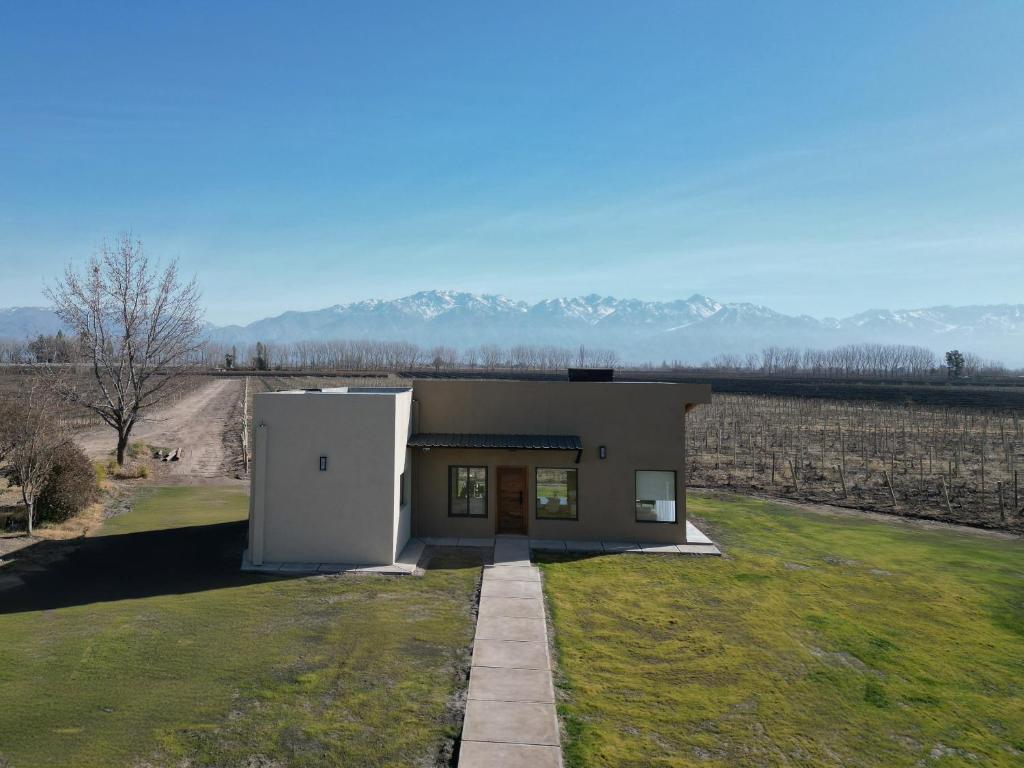 Un pequeño edificio en un campo de hierba con montañas al fondo. en Las Nencias Houses, en San Carlos