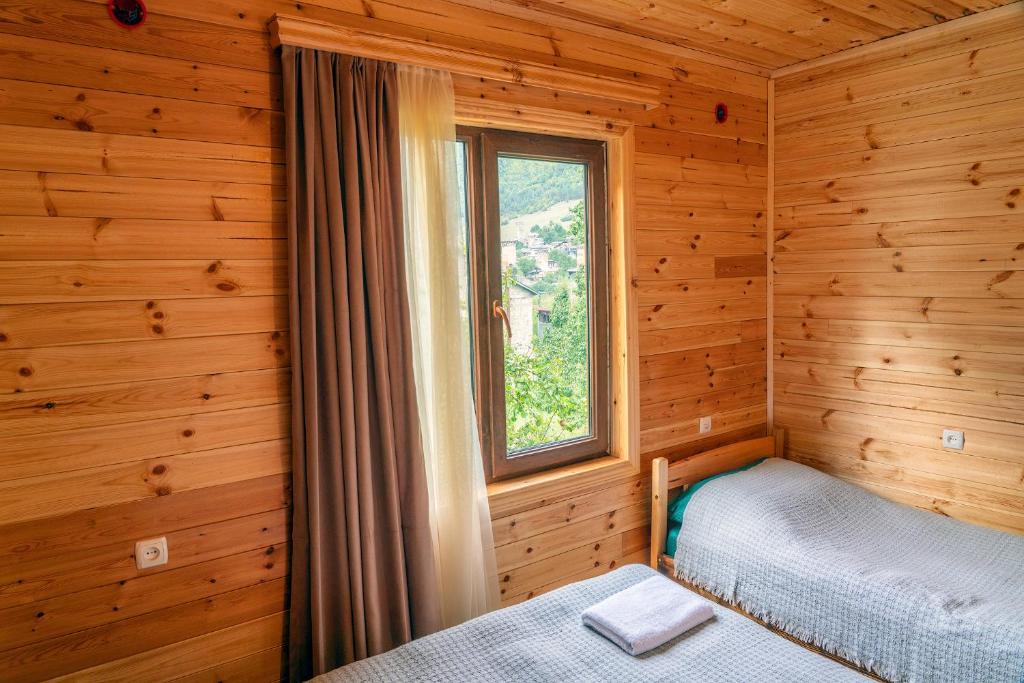 una camera da letto in una baita di tronchi con finestra di Ioane's Chalet a Mestia