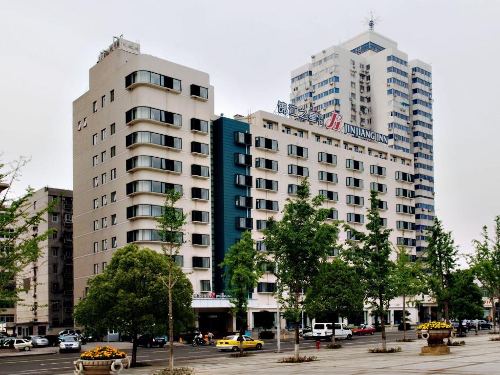 two tall buildings in a city with a parking lot at Jinjiang Inn Select Wuhan Chu Hehan Street Shuiguohu in Wuhan