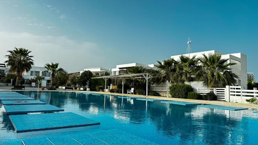 a large swimming pool with blue mats in front of a building at Вилла в жилом комплексе Caesar Beach V16L in Boğaz