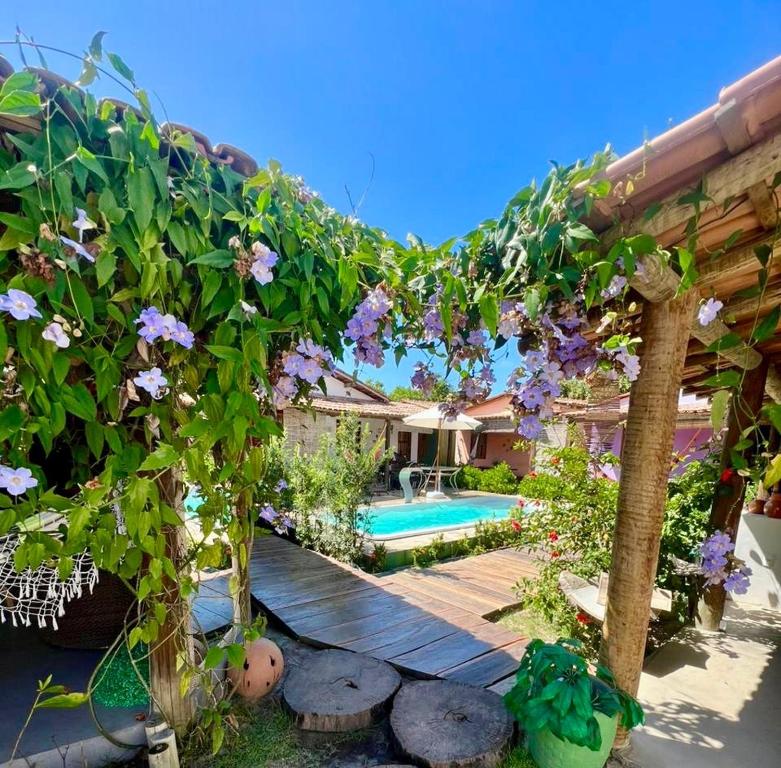 a backyard with a pool and a pergola with purple flowers at Casa 02 na villa uryah in Caraíva