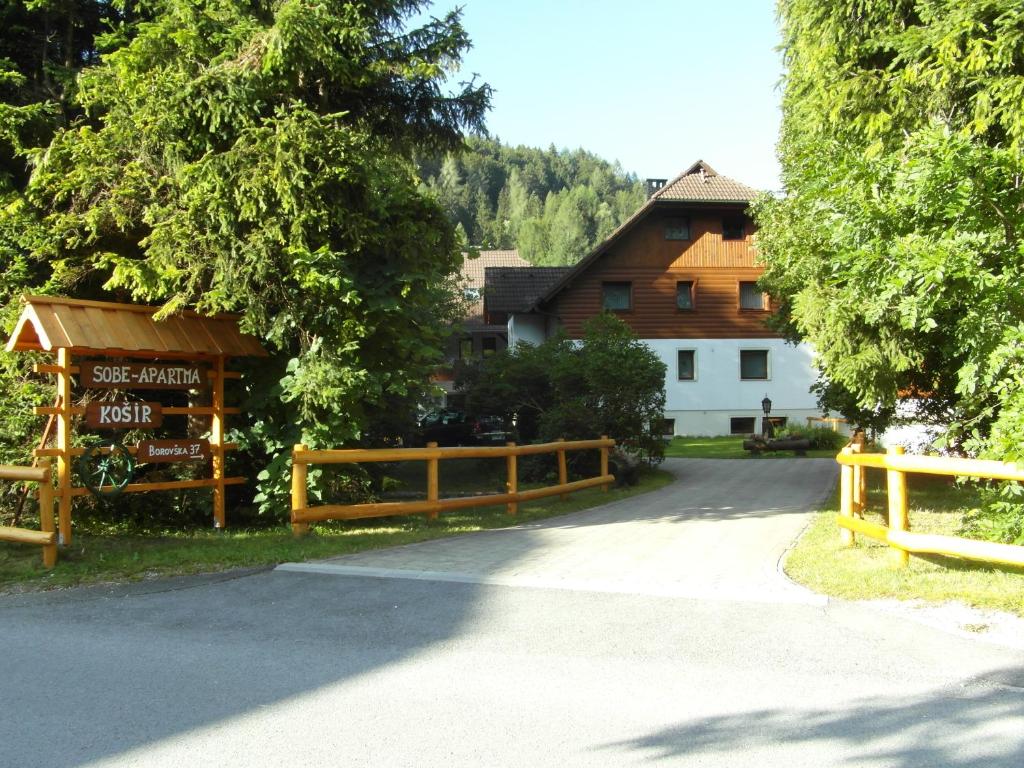 una recinzione di legno accanto a un edificio e a una casa di Farm Košir a Kranjska Gora