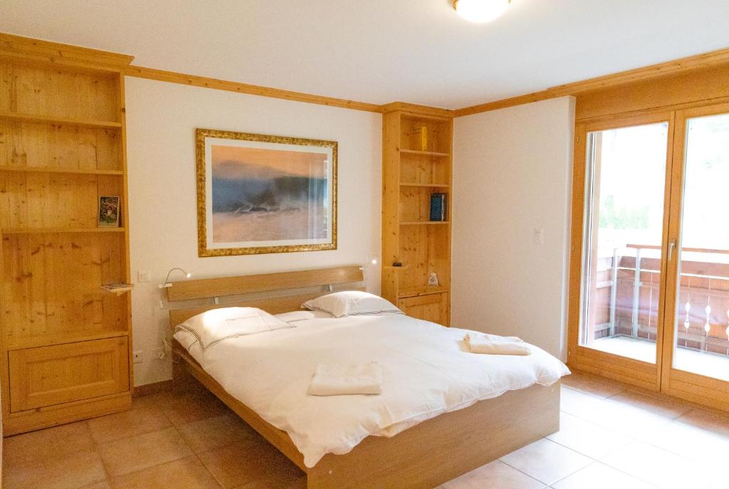 a bedroom with a bed and a large window at Résidence Grenon in Crans-Montana