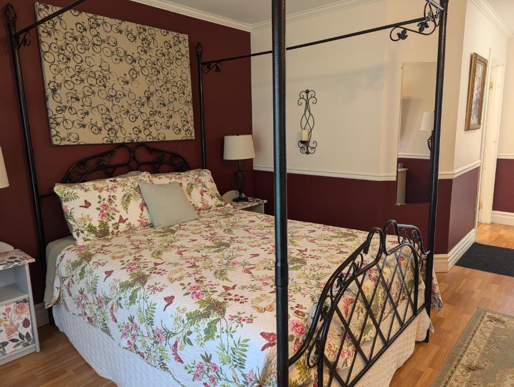 a bedroom with a canopy bed with a floral bedspread at The Parrsboro Mansion Inn in Parrsboro