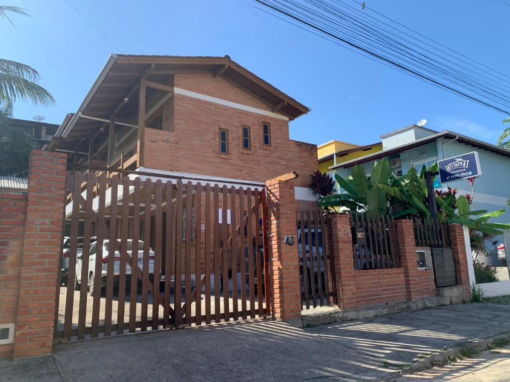a brick house with a wooden gate in front at Pousada Latitude 27 Bombinhas in Bombinhas