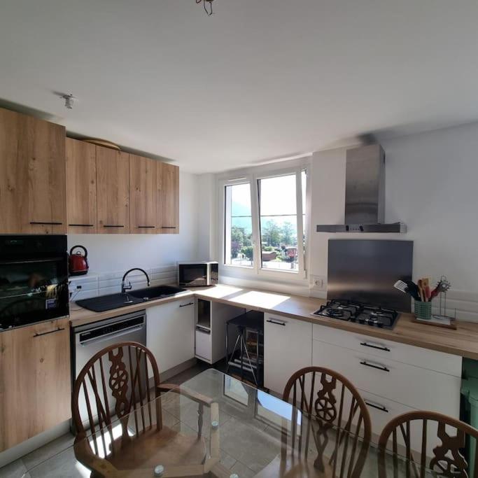 une cuisine avec des armoires blanches et une table et des chaises dans l'établissement Appartement de la Villa du port, à Sévrier