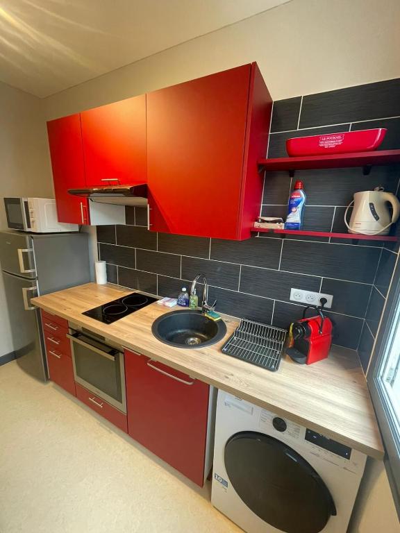 une petite cuisine avec des armoires rouges et un évier dans l'établissement Appartement proche de l'hôpital, à Tulle