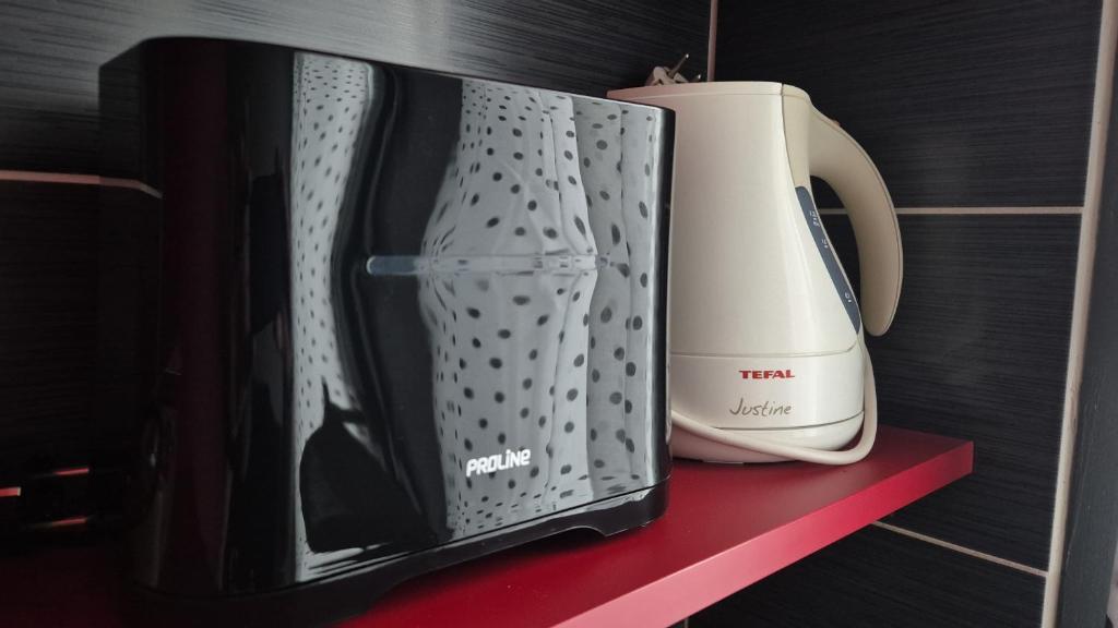 a black and white toaster sitting on a red shelf at Appartement proche de l'hôpital in Tulle