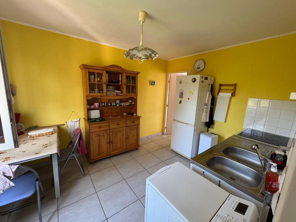 - une cuisine avec des murs jaunes et un réfrigérateur blanc dans l'établissement Maison 6P à Saint Nazaire en Roussillon, entre Canet plage et Saint Cyprien, à Saint-Nazaire