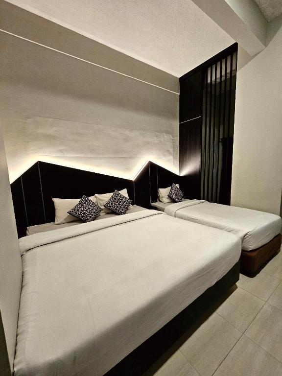 two beds in a hotel room with white sheets at Airlangga Hotel in Yogyakarta