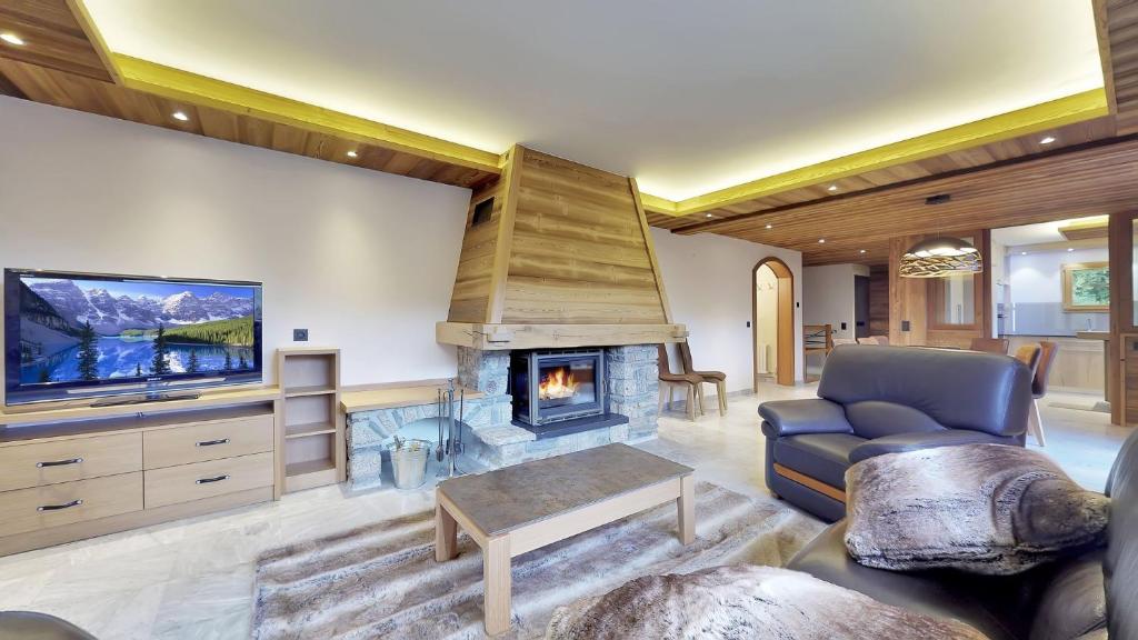un salon avec une cheminée et une télévision dans l'établissement Chalet Orchidee Megeve sur les pistes, à Megève