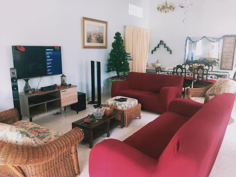 a living room with red couches and a tv at Pet-Friendly, Spacious Family Cottage, with Games Lounge & Near Beach in Port Dickson