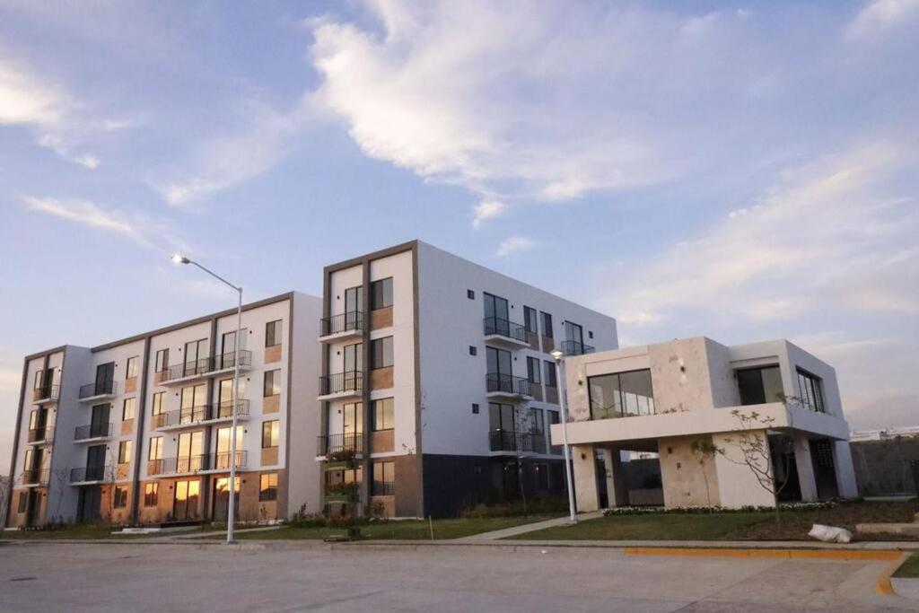 ein großes weißes Gebäude vor einem Parkplatz in der Unterkunft Departamento Ejecutivo cerca de BJX in Santa Gertrudis